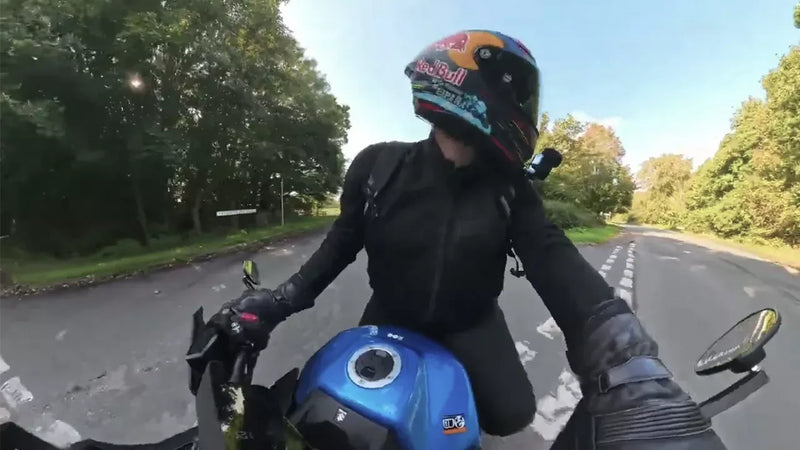 Person riding a motorcycle on a road with trees in the background