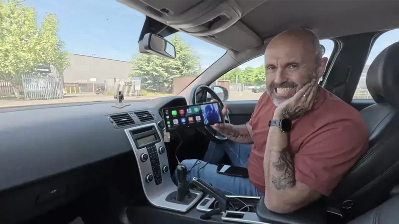 Man sitting inside a car with a smartphone app displayed on the screen